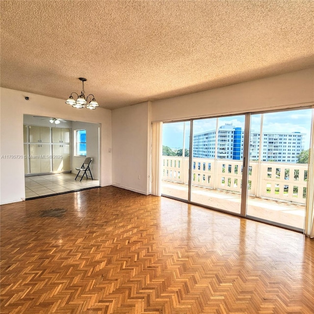 empty room with an inviting chandelier and a textured ceiling