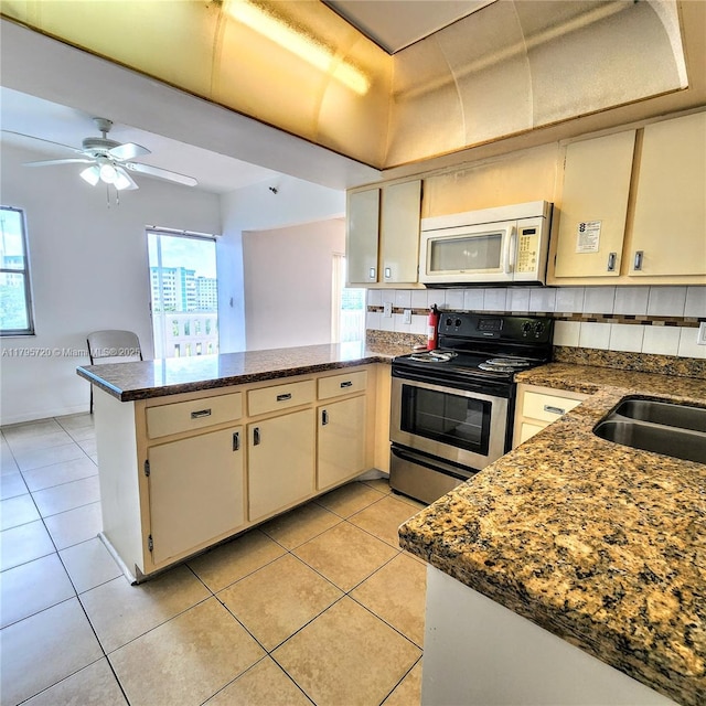 kitchen featuring a peninsula, tasteful backsplash, white microwave, and electric range