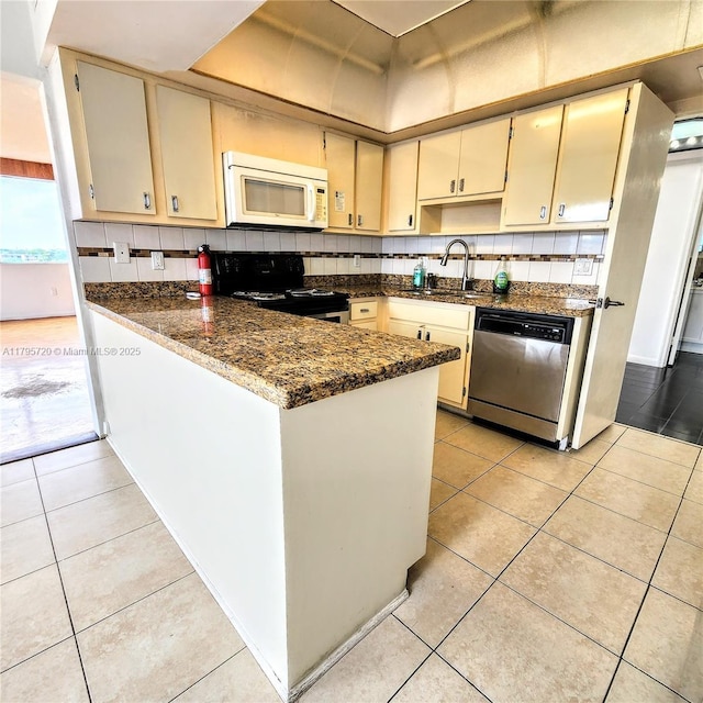 kitchen with electric range, a peninsula, white microwave, a sink, and dishwasher