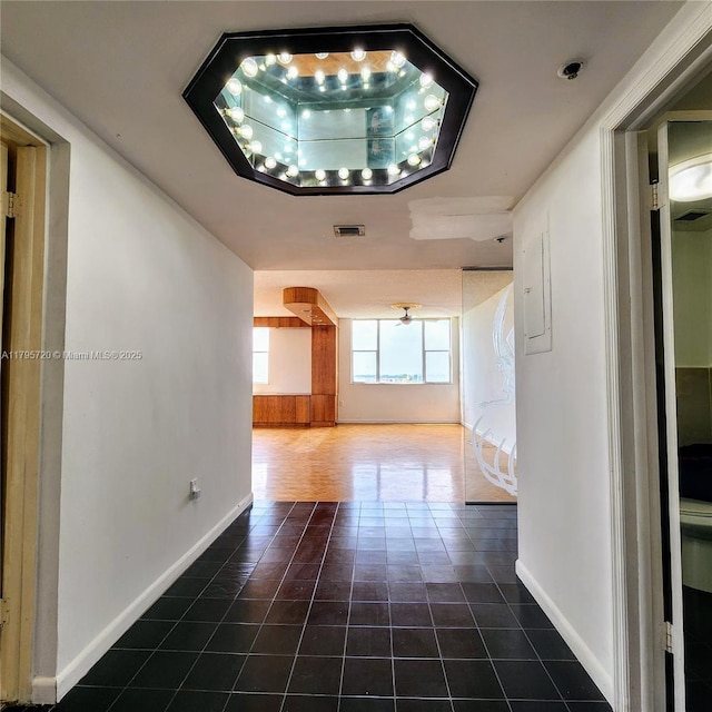 corridor featuring visible vents, baseboards, and tile patterned flooring