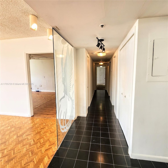 hall with baseboards and electric panel