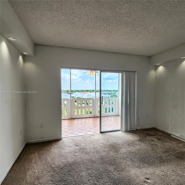 carpeted empty room with a textured ceiling and baseboards