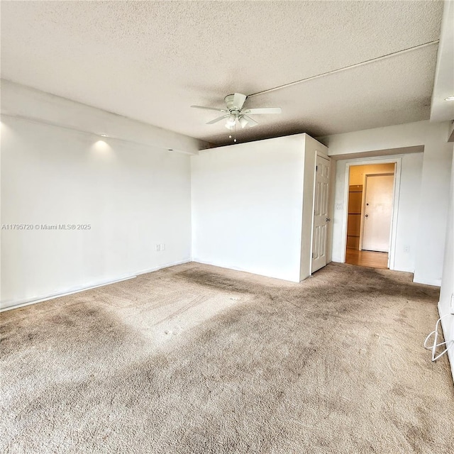 carpeted spare room featuring baseboards, a ceiling fan, and a textured ceiling