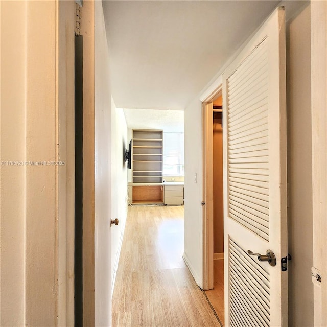 hall featuring baseboards and light wood-type flooring