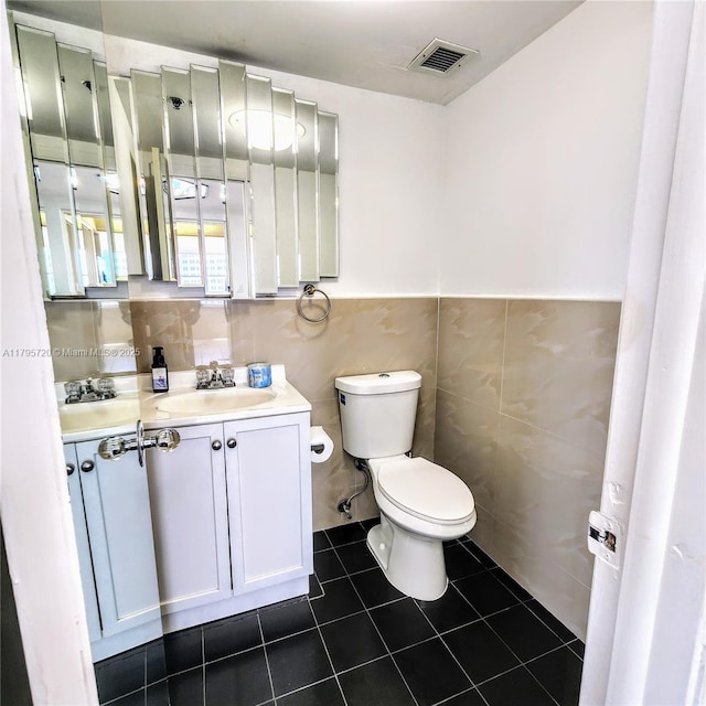 bathroom with visible vents, tile walls, tile patterned flooring, vanity, and toilet