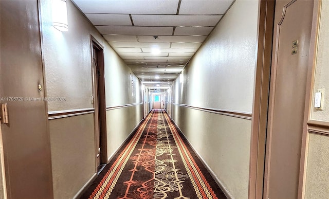 corridor featuring a textured wall and a drop ceiling