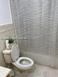 bathroom with tile patterned flooring, vanity, toilet, tile walls, and a shower with curtain