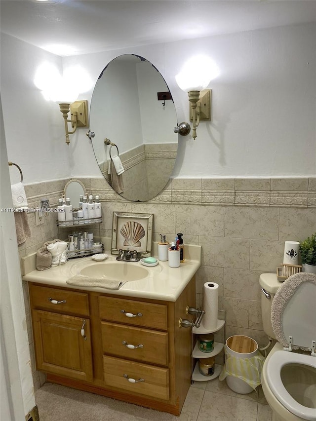 half bath featuring tile walls, tile patterned flooring, vanity, and toilet