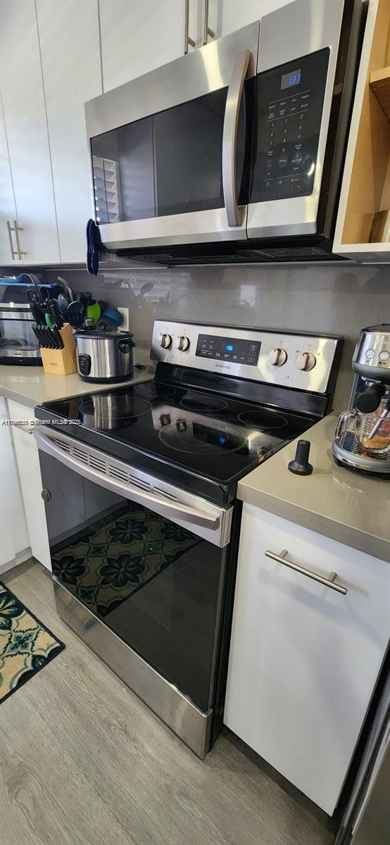 kitchen featuring white cabinets, stainless steel appliances, and light wood-style flooring