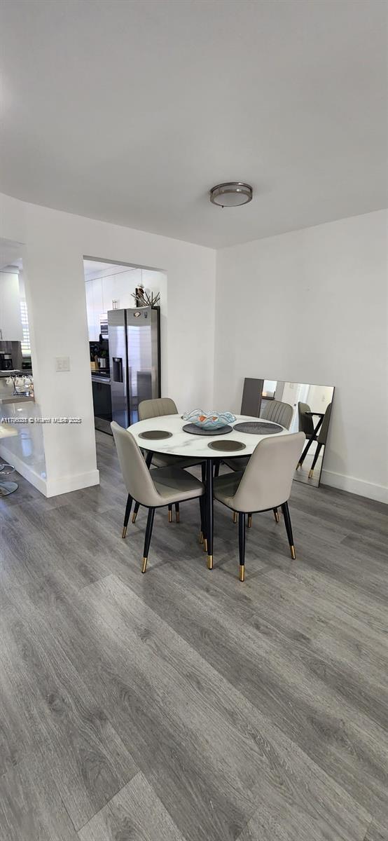 dining area with baseboards, dark wood finished floors, and a notable chandelier