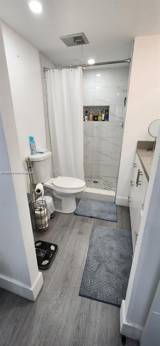 full bathroom featuring toilet, visible vents, a shower stall, and wood finished floors