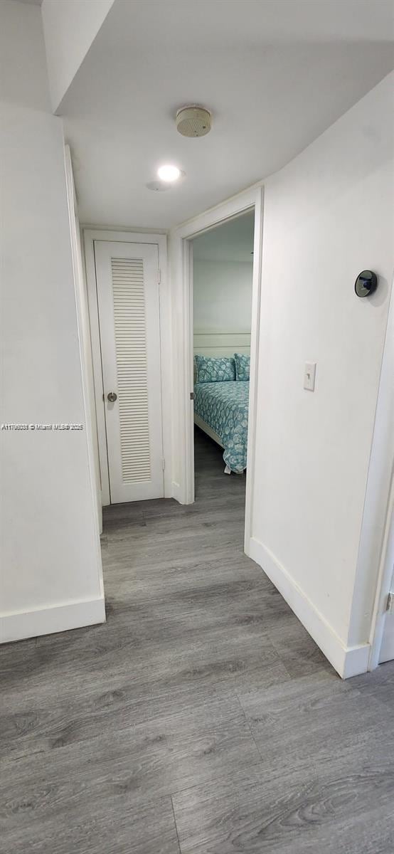 corridor with baseboards and wood finished floors
