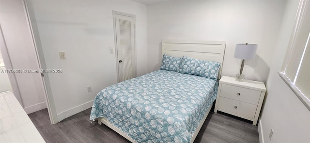bedroom featuring baseboards, dark wood finished floors, and a closet
