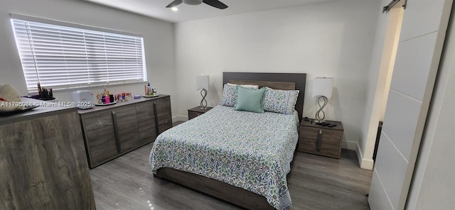 bedroom with baseboards, a barn door, a ceiling fan, and wood finished floors