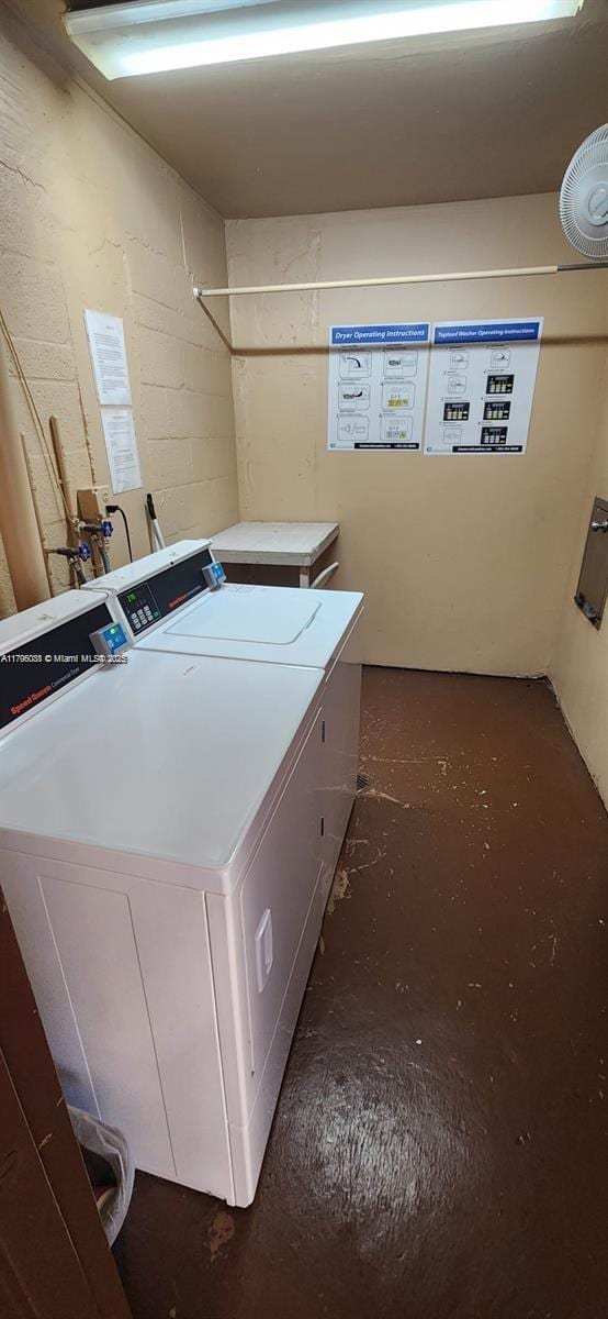 common laundry area featuring concrete block wall and washer and clothes dryer