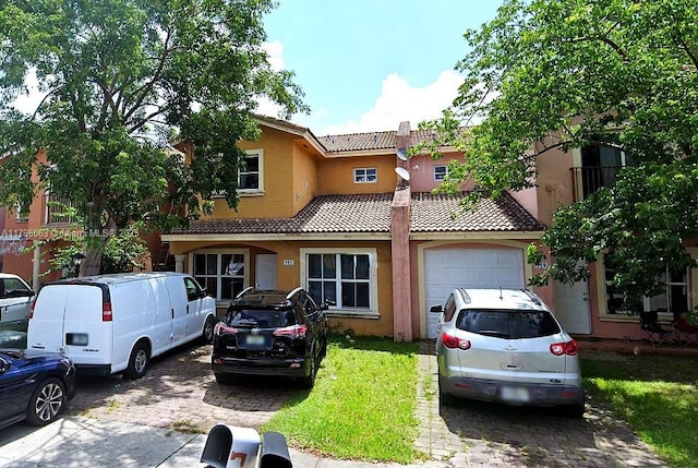 view of front of home featuring a tiled roof, an attached garage, driveway, and stucco siding