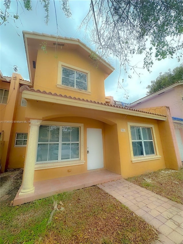 back of house featuring stucco siding and a tile roof