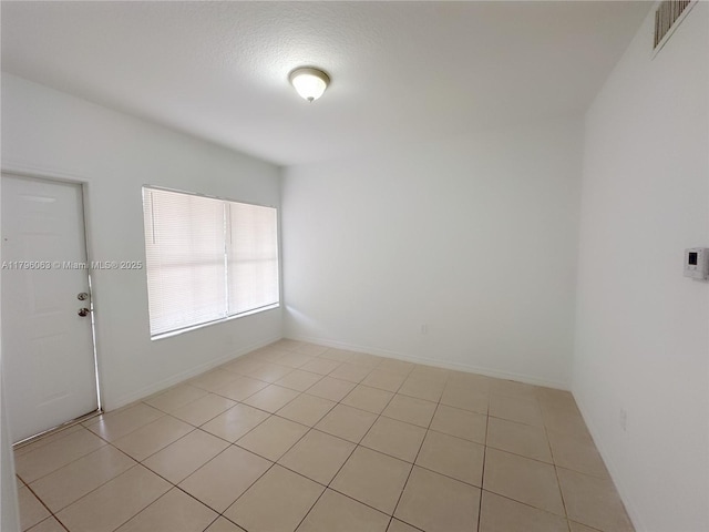empty room with light tile patterned floors, baseboards, and visible vents