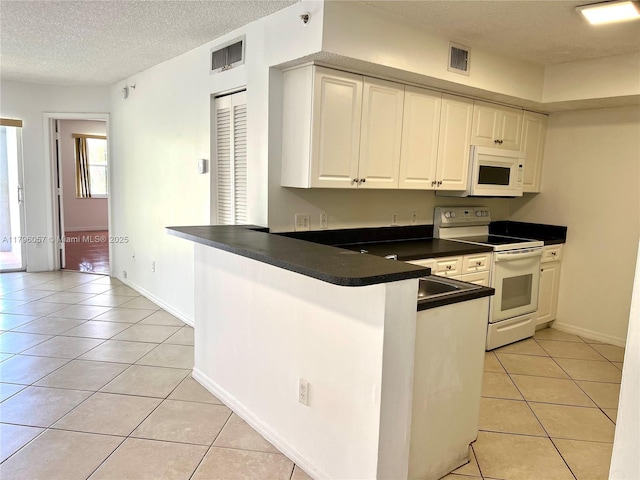 kitchen with dark countertops, white appliances, a peninsula, light tile patterned floors, and visible vents