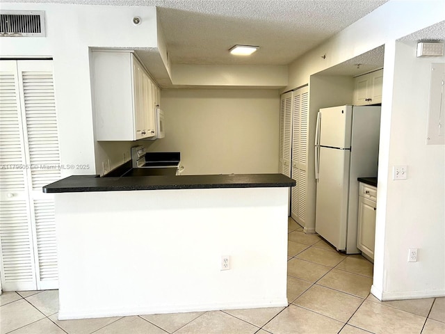 kitchen featuring dark countertops, white appliances, a peninsula, light tile patterned floors, and visible vents