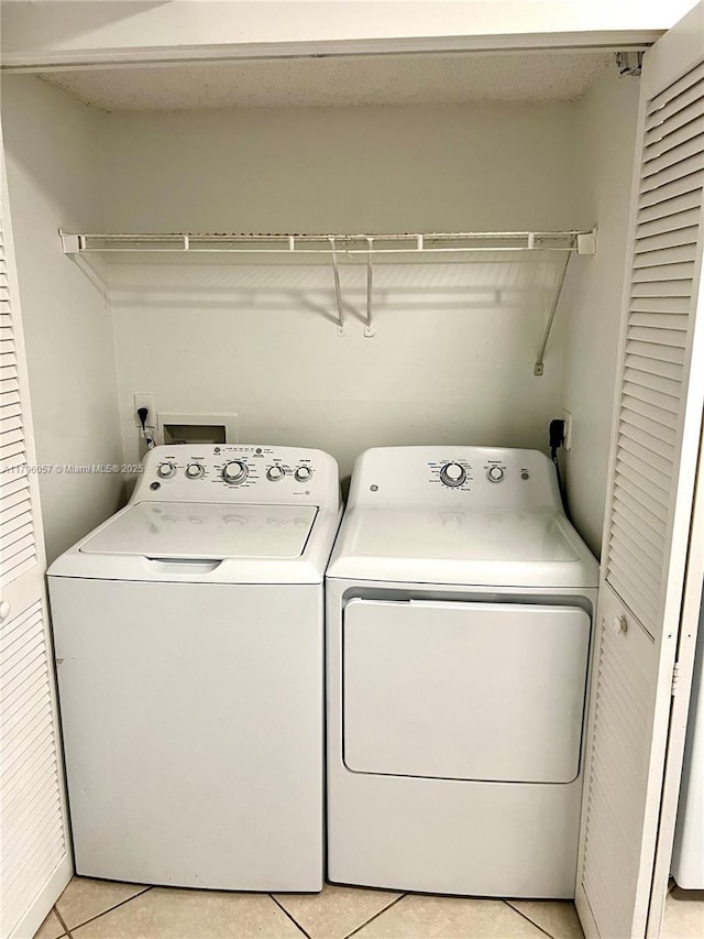 laundry room with laundry area, washing machine and dryer, and light tile patterned floors