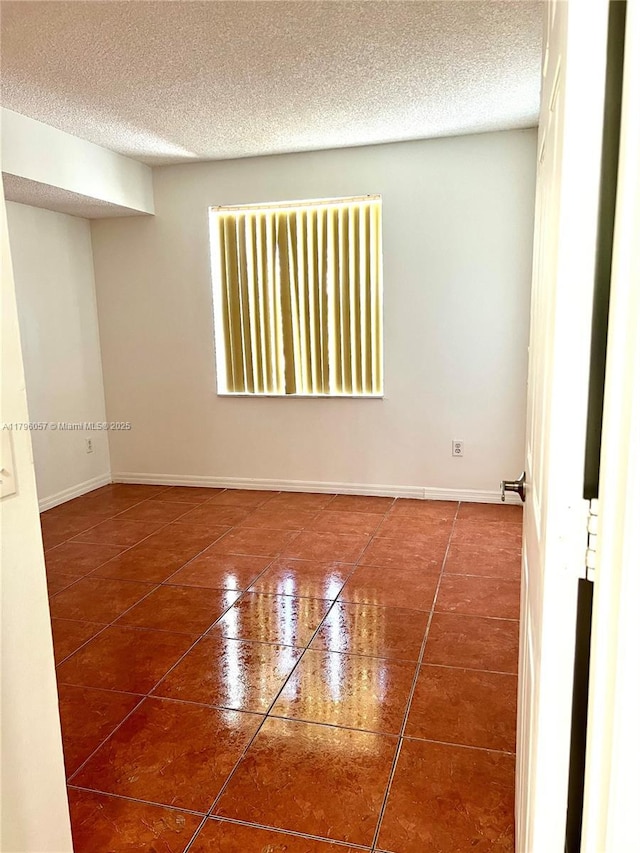 spare room with tile patterned floors, baseboards, and a textured ceiling