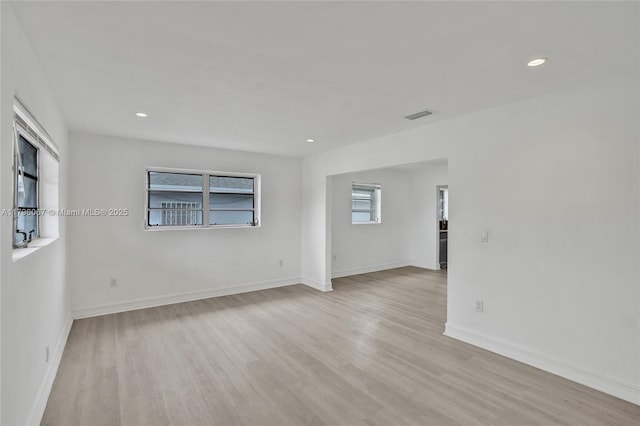 unfurnished room featuring baseboards, light wood finished floors, and visible vents