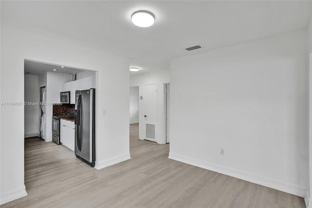 unfurnished living room featuring visible vents, light wood-style flooring, and baseboards