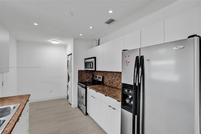 kitchen featuring decorative backsplash, dark countertops, light wood-type flooring, stainless steel appliances, and recessed lighting