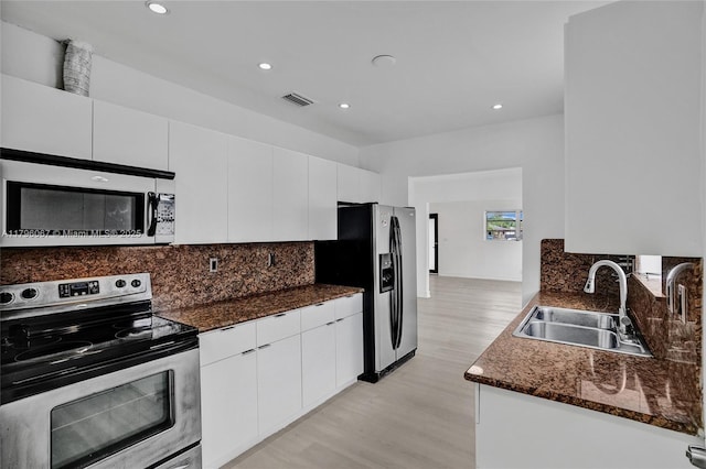 kitchen featuring appliances with stainless steel finishes, tasteful backsplash, a sink, and light wood-style floors