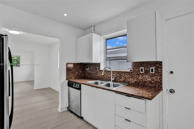 kitchen with baseboards, a sink, appliances with stainless steel finishes, and dark countertops