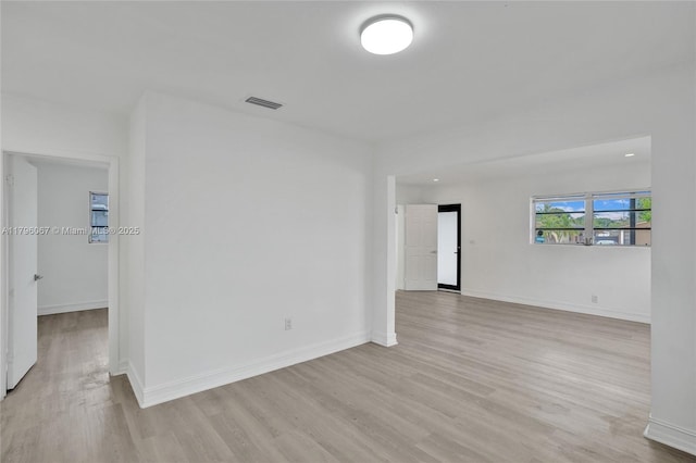 spare room featuring baseboards, visible vents, and light wood-style floors
