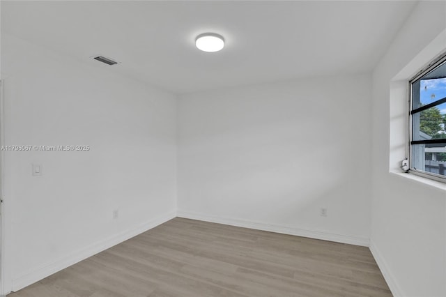 unfurnished room with baseboards, visible vents, and wood finished floors