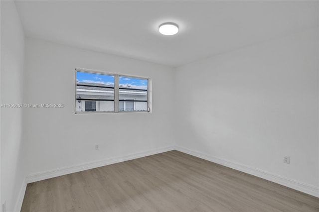 spare room featuring baseboards and wood finished floors