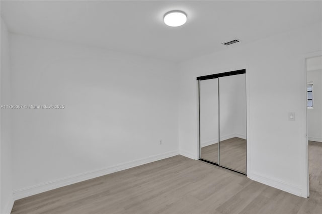 unfurnished bedroom featuring baseboards, a closet, light wood-type flooring, and visible vents
