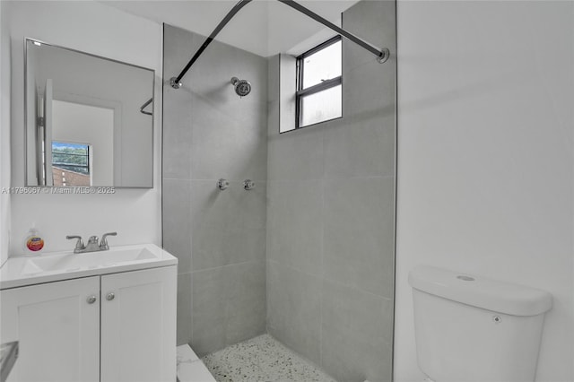 full bath featuring vanity, a tile shower, and toilet