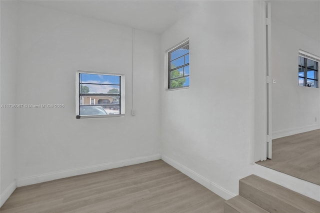 spare room with baseboards and light wood-style flooring