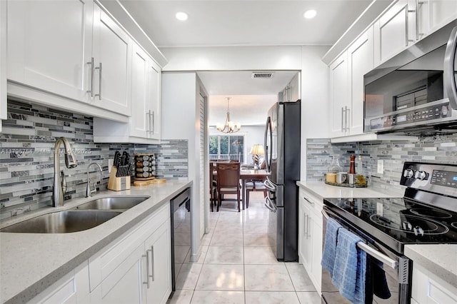 kitchen with visible vents, white cabinetry, a sink, backsplash, and stainless steel appliances