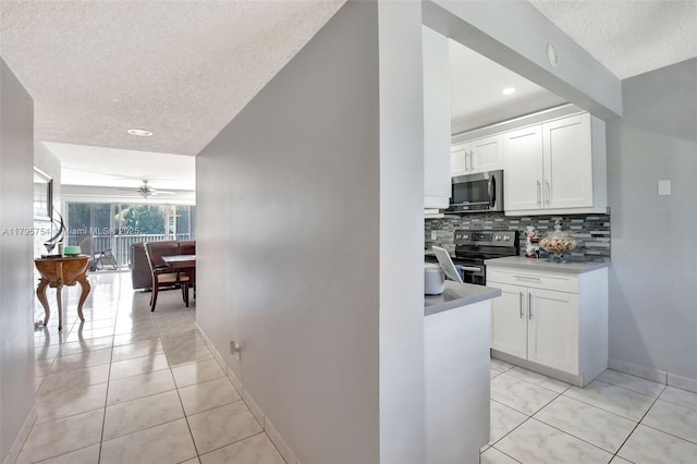 hallway featuring light tile patterned floors, baseboards, recessed lighting, and a textured ceiling