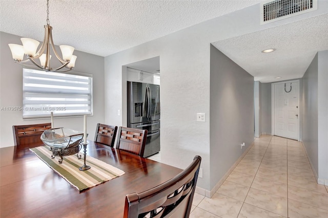 dining space with light tile patterned floors, a textured ceiling, visible vents, and an inviting chandelier