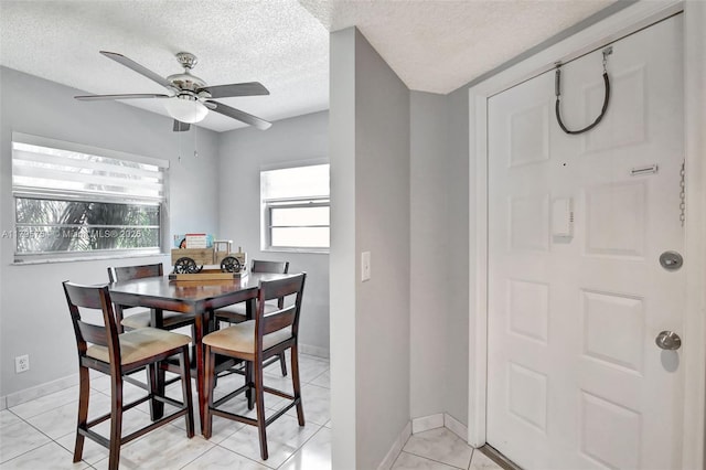 dining space featuring baseboards, a ceiling fan, and a textured ceiling