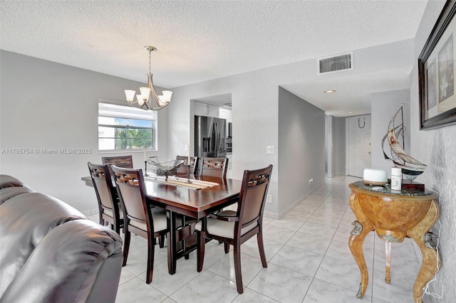 dining space featuring a chandelier, a textured ceiling, and visible vents