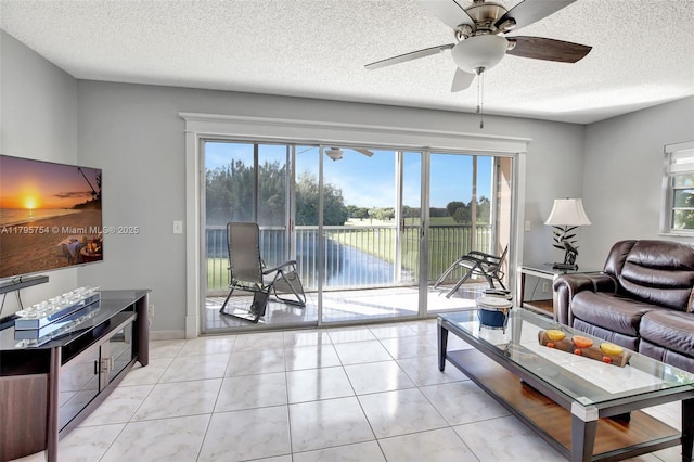 living area featuring a ceiling fan, a textured ceiling, and a water view