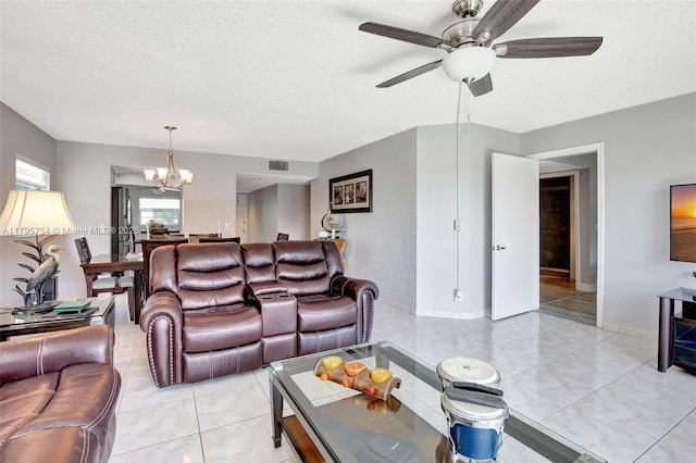 living area with a textured ceiling, visible vents, light tile patterned floors, and ceiling fan with notable chandelier