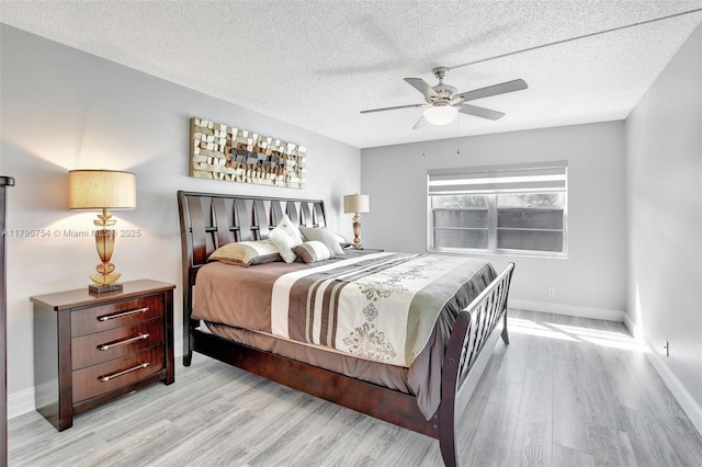bedroom featuring a textured ceiling, baseboards, a ceiling fan, and light wood-style flooring