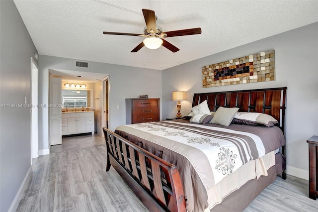 bedroom featuring a ceiling fan, a textured ceiling, visible vents, wood finished floors, and baseboards