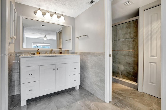 bathroom featuring tile walls, a shower stall, a textured ceiling, and visible vents