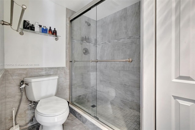 bathroom with tile walls, a shower stall, and toilet