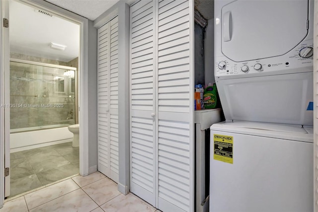 laundry room with laundry area, stacked washer and clothes dryer, light tile patterned flooring, and visible vents