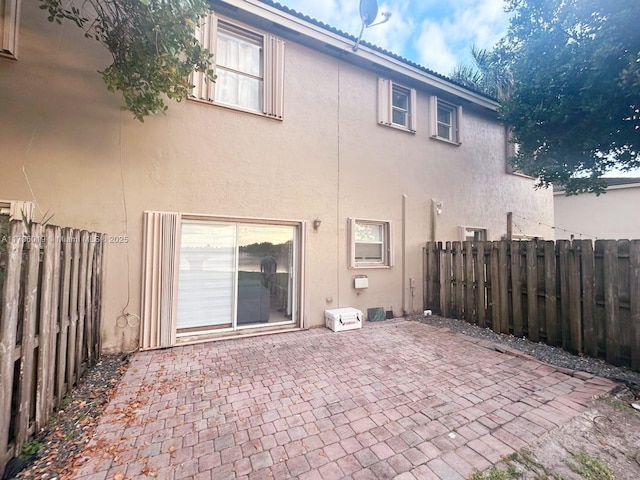rear view of property with a patio, a fenced backyard, and stucco siding